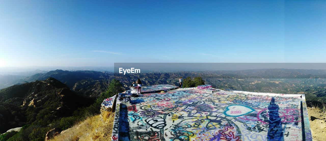 Panoramic view of landscape against blue sky with art graffiti 