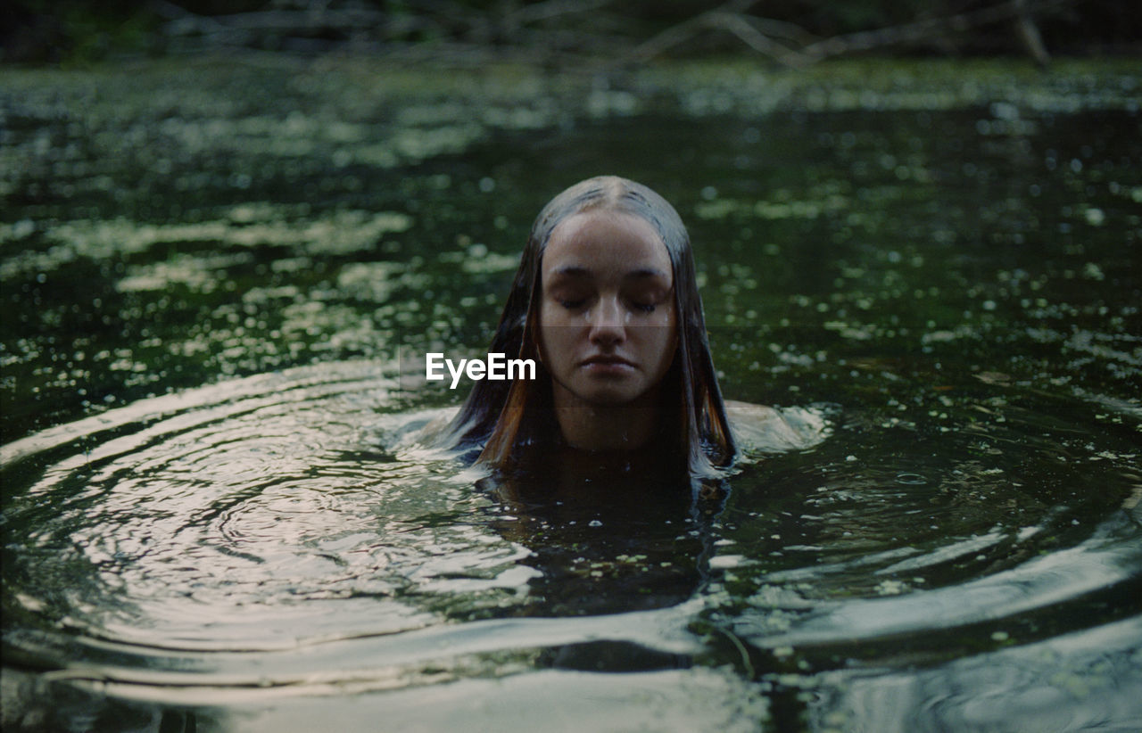 A woman in a white dress on the surface of a swamp water in the forest