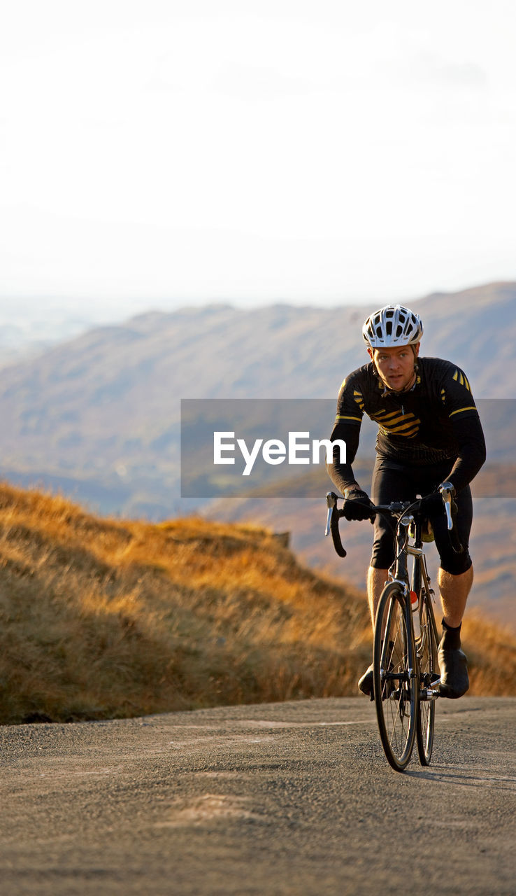 Cyclist approaching top of hill in the british lake district