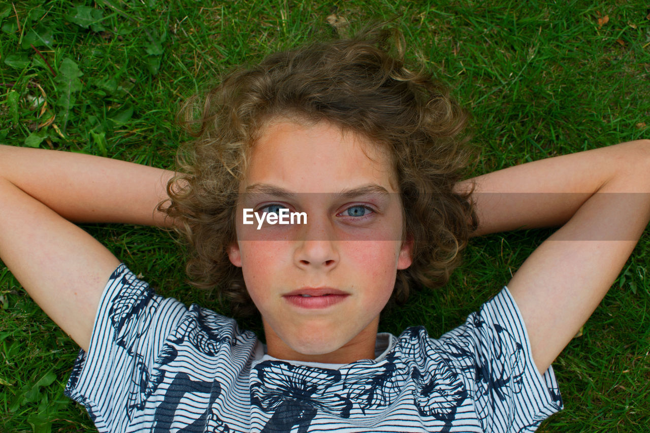 Portrait of boy relaxing on grassy field at park