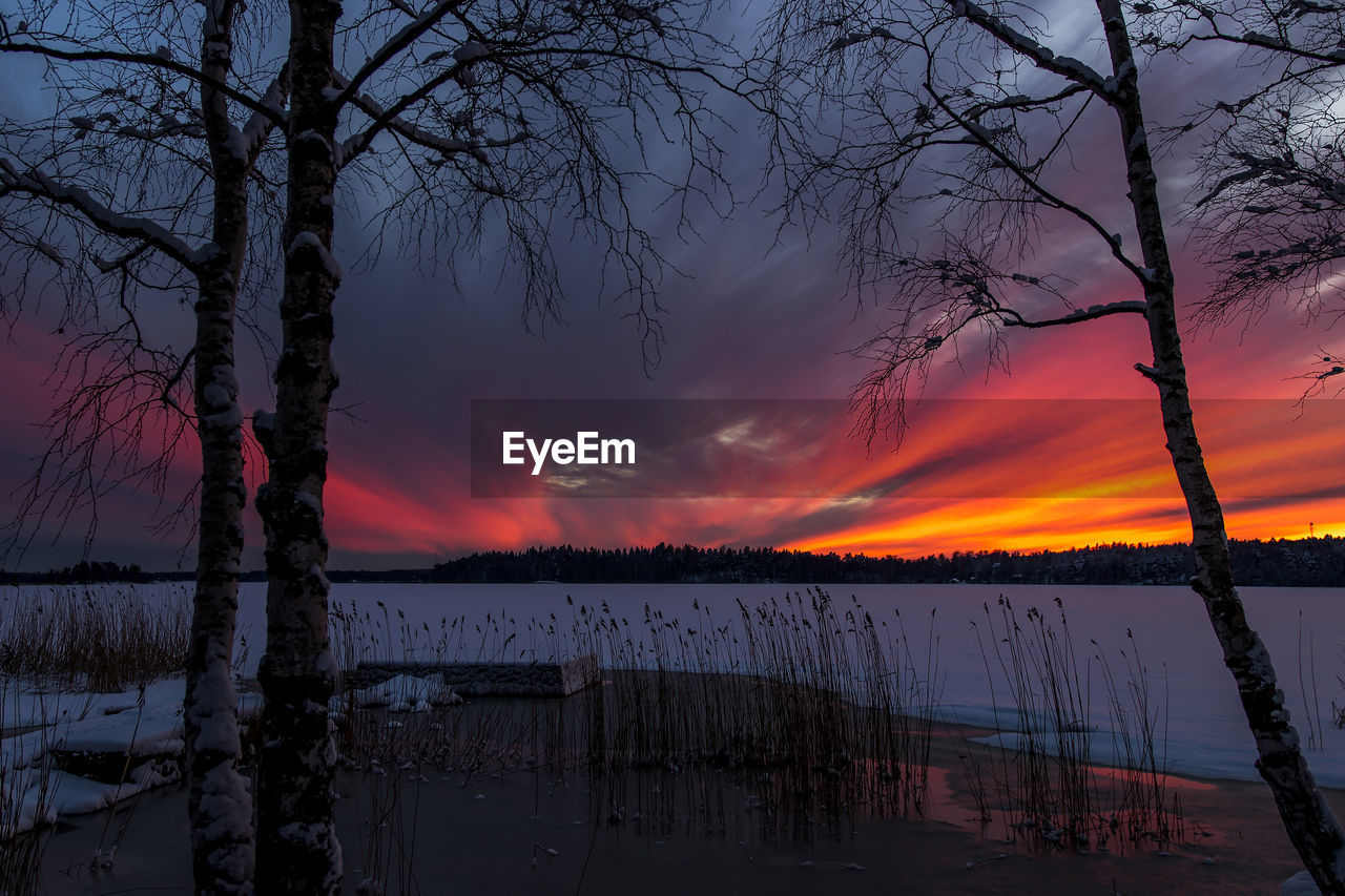 Scenic view of frozen lake against cloudy sky during sunset