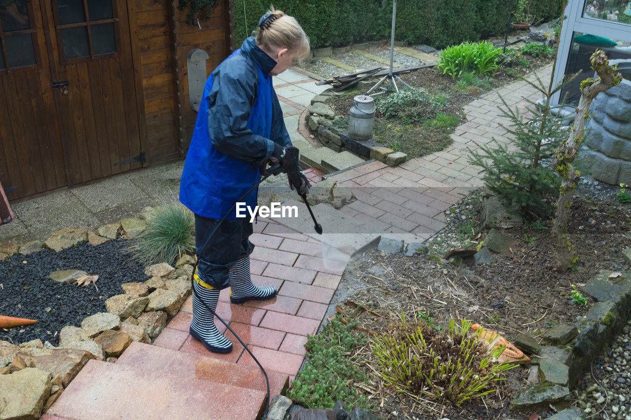 Woman cleaning footpath with hose