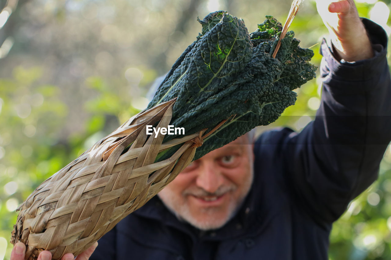 PORTRAIT OF SMILING MAN HOLDING LEAF IN PARK