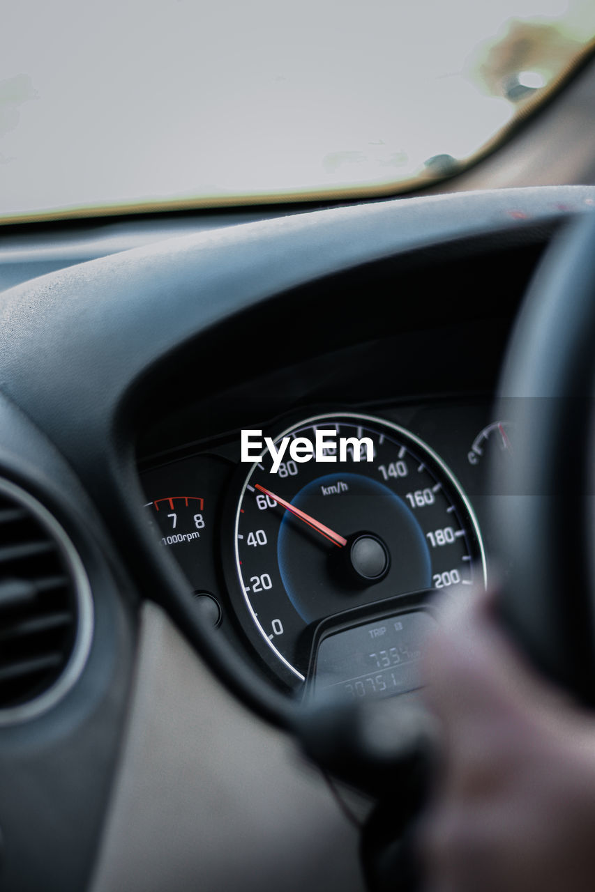 Cropped hand holding steering wheel while sitting at car