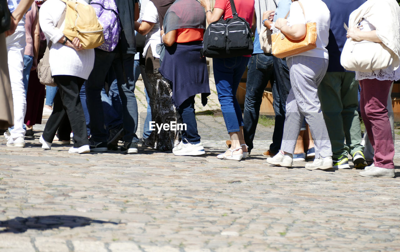 LOW SECTION OF PEOPLE STANDING ON ROAD