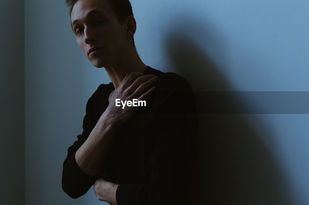 Portrait of young man standing against blue wall