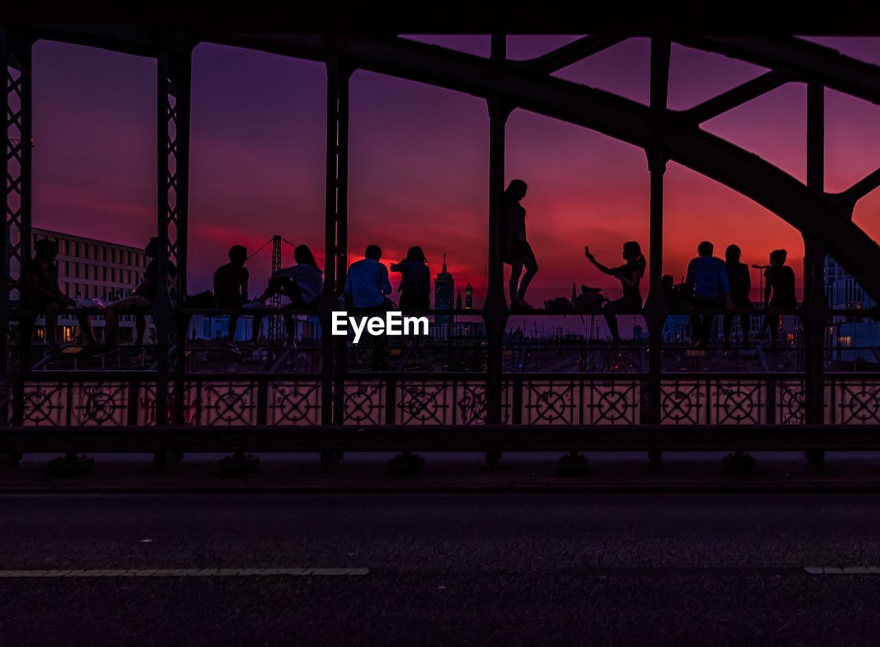 Silhouette people at observation point against sky during sunset