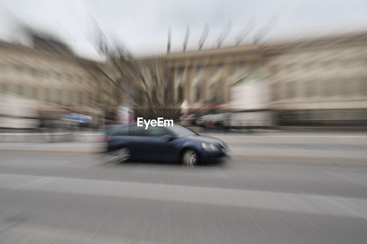 BLURRED MOTION OF CAR ON STREET AGAINST BUILDINGS