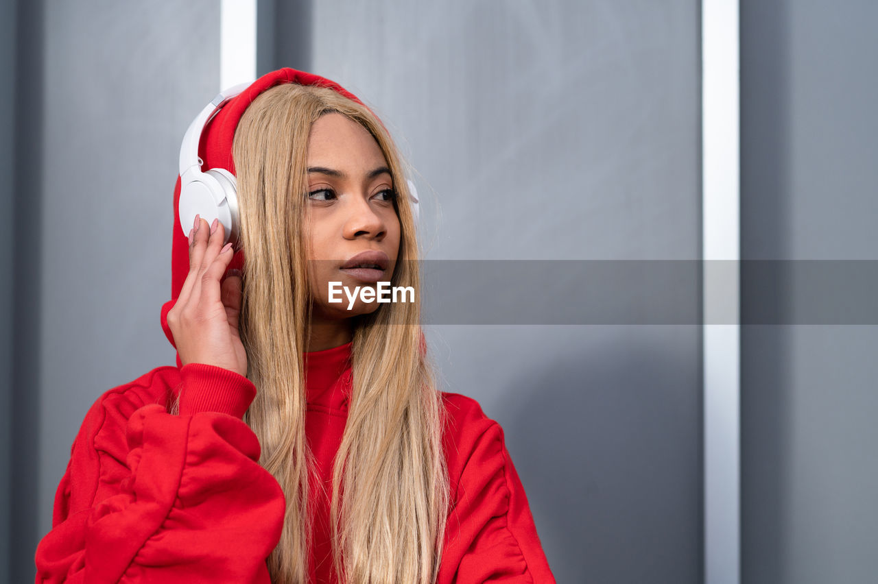 Cheerful african american woman with long blonde hair wearing sportswear and wearing headphones