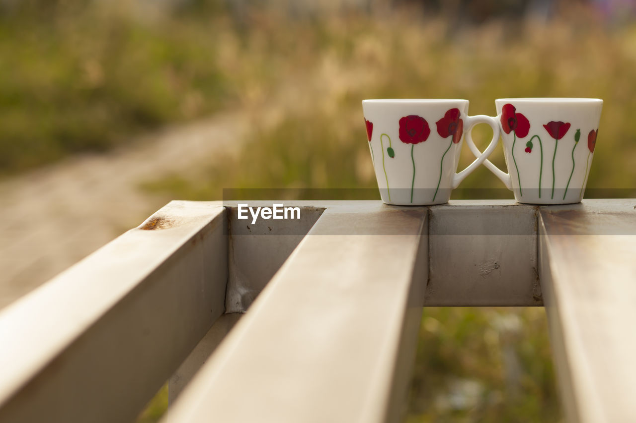 Close-up of coffee cups on railing