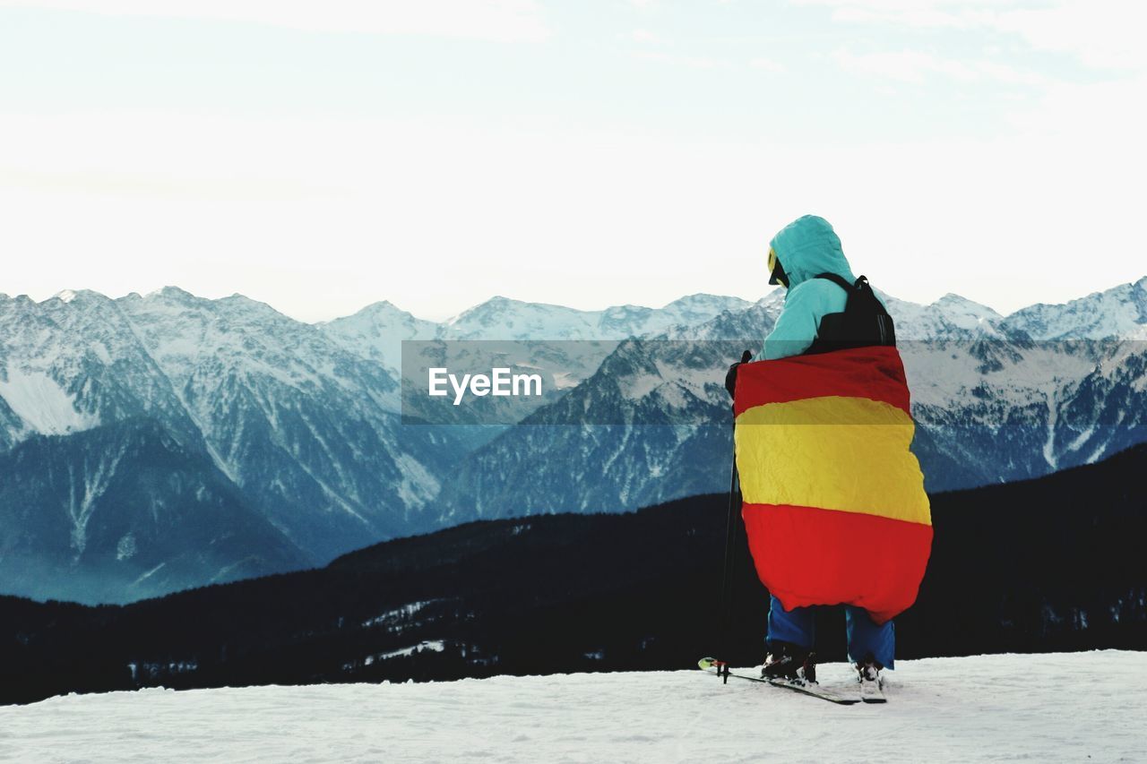 Rear view of man walking on snow covered mountain