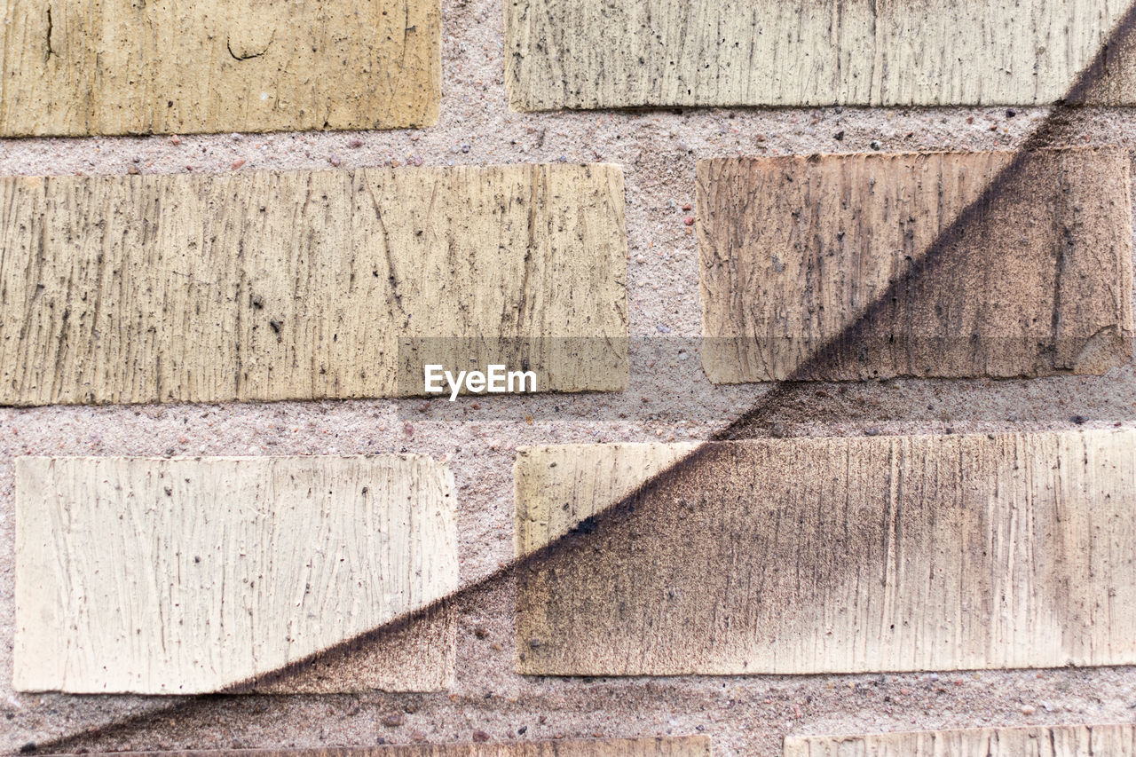 Black spray paint curve on yellow brick wall.