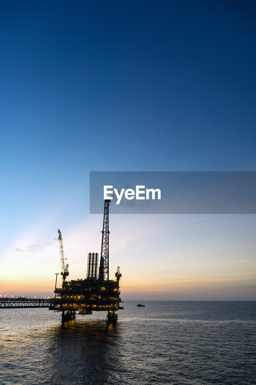 Silhouette of oil production platform during sunset at offshore oil field