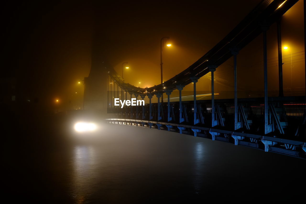 Illuminated bridge over river against sky at night