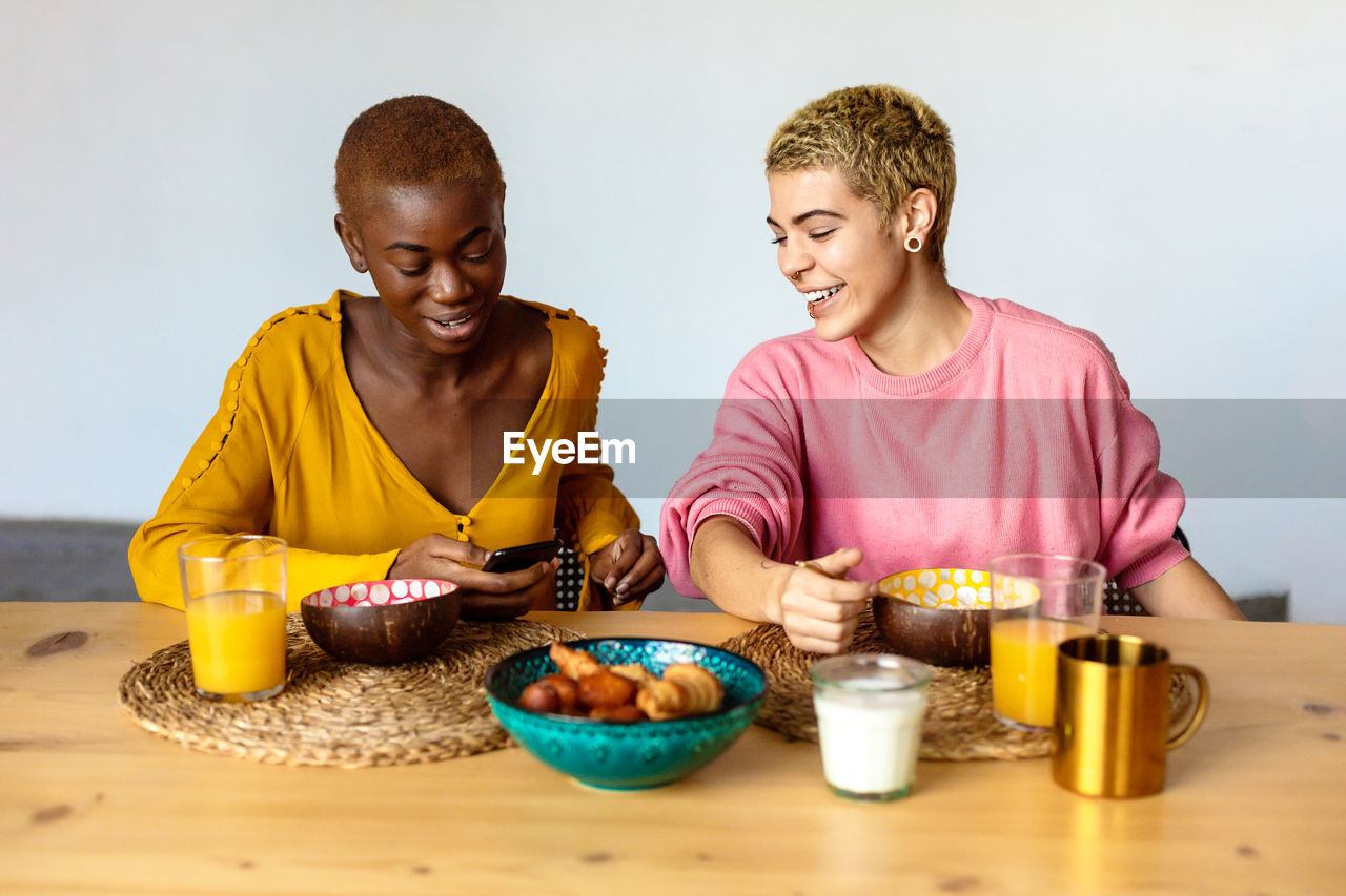 Cheerful lesbian couple using smart phone at home