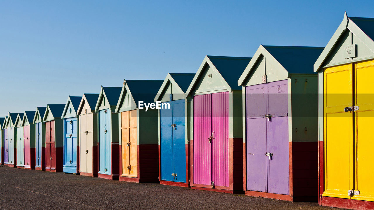 Multi colored beach huts against clear blue sky