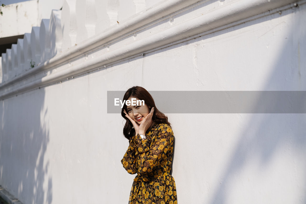 Woman smiling while standing against wall