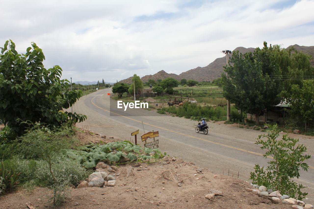 ROAD PASSING THROUGH LANDSCAPE AGAINST CLOUDY SKY