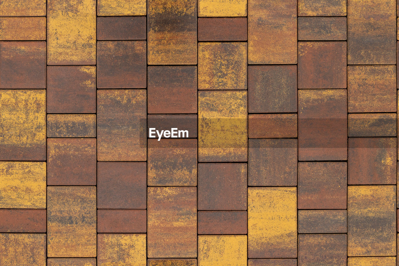 Seamless texture and background of brown and yellow melange rectangular artificial stone pavement