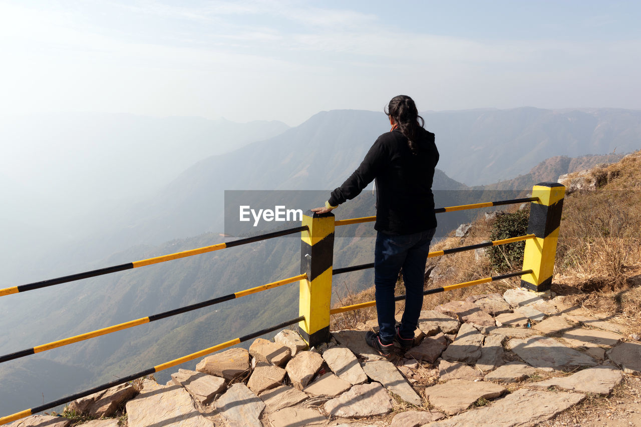 Full length of man standing on railing against mountain