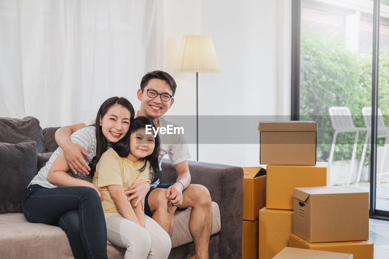 Smiling family packing cardboard while sitting at home