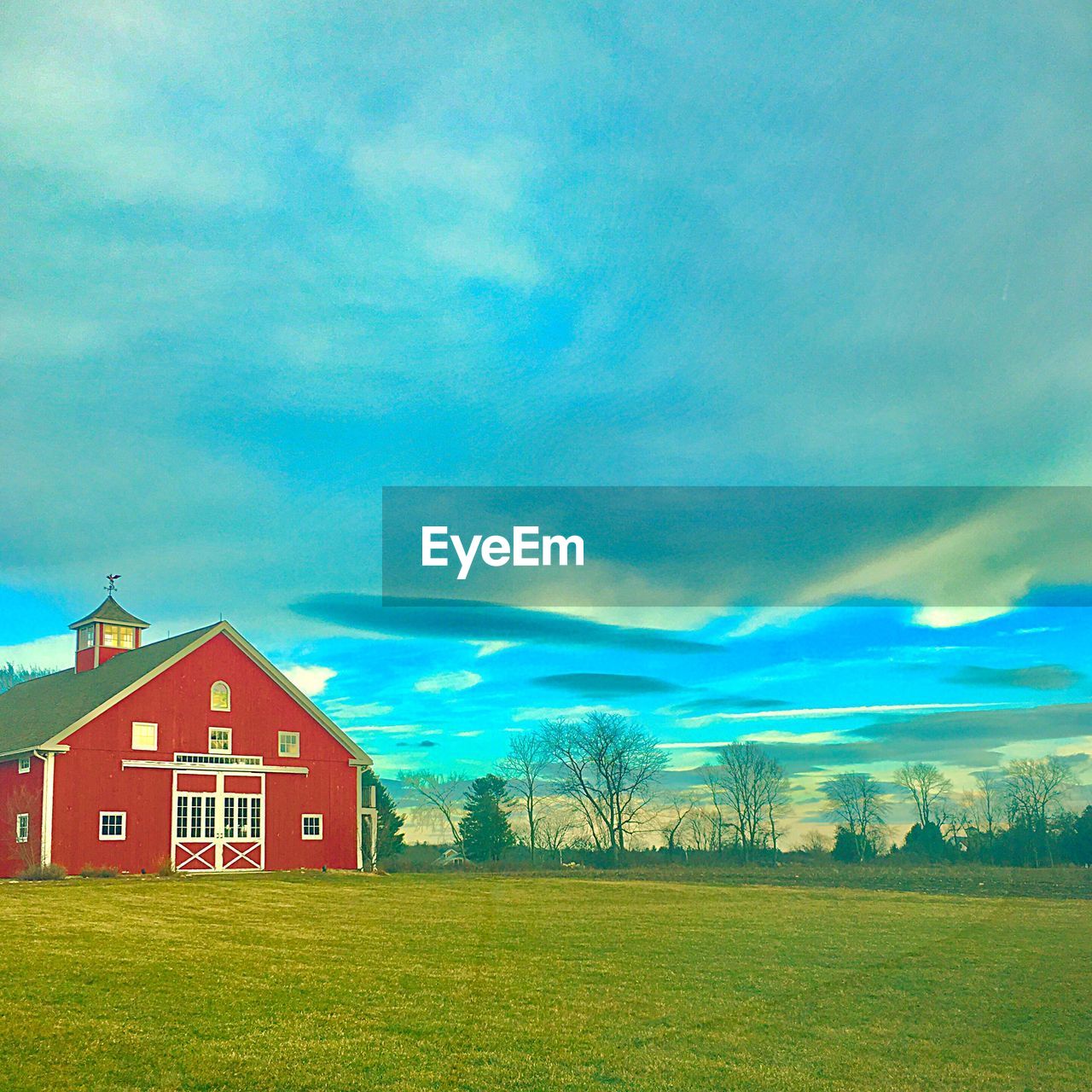 HOUSE ON FIELD AGAINST BLUE SKY