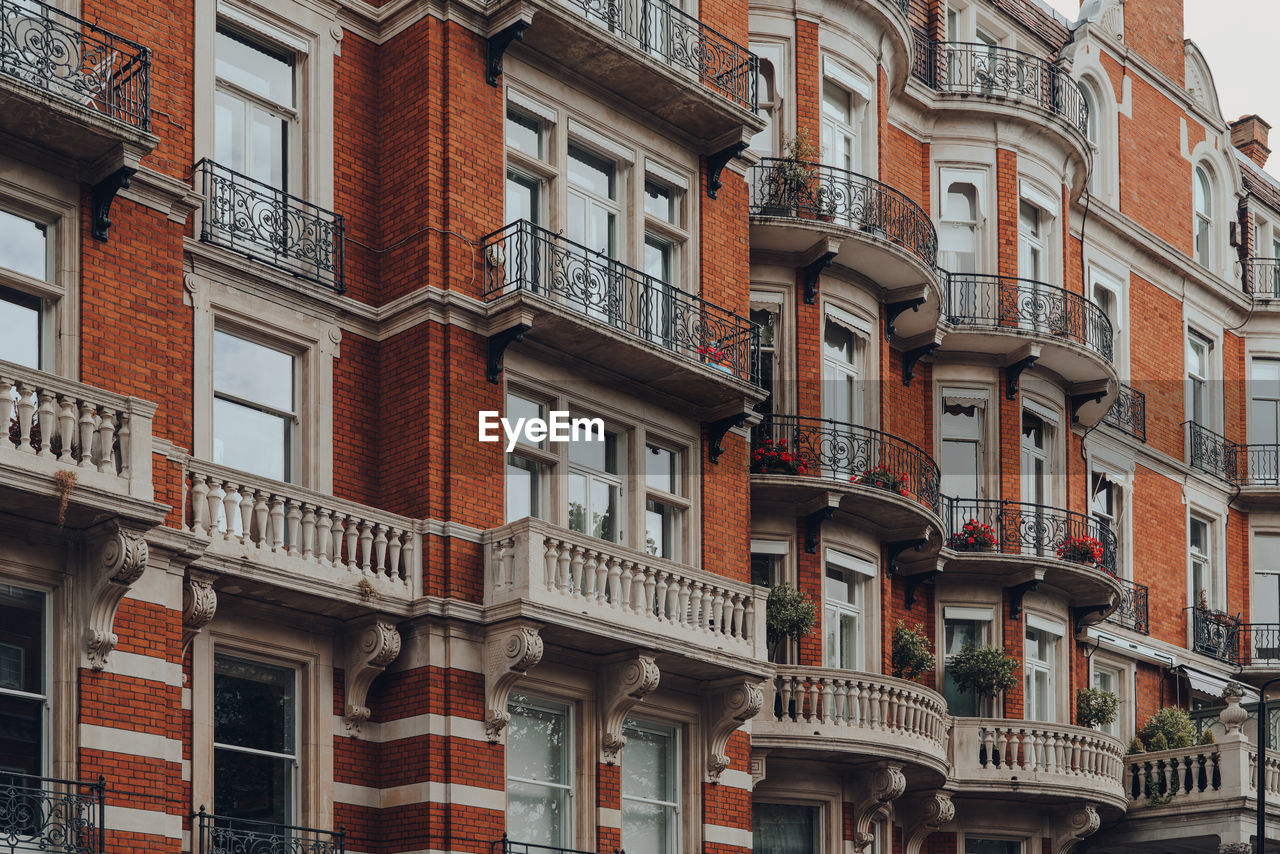 Exterior of a traditional red brick apartment block with balconies in kensington, london, uk.