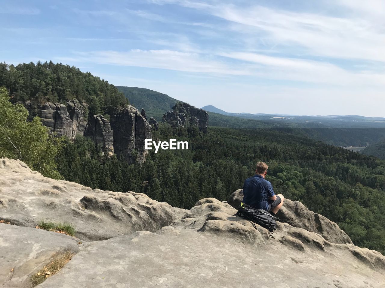 Man sitting on rock against mountains