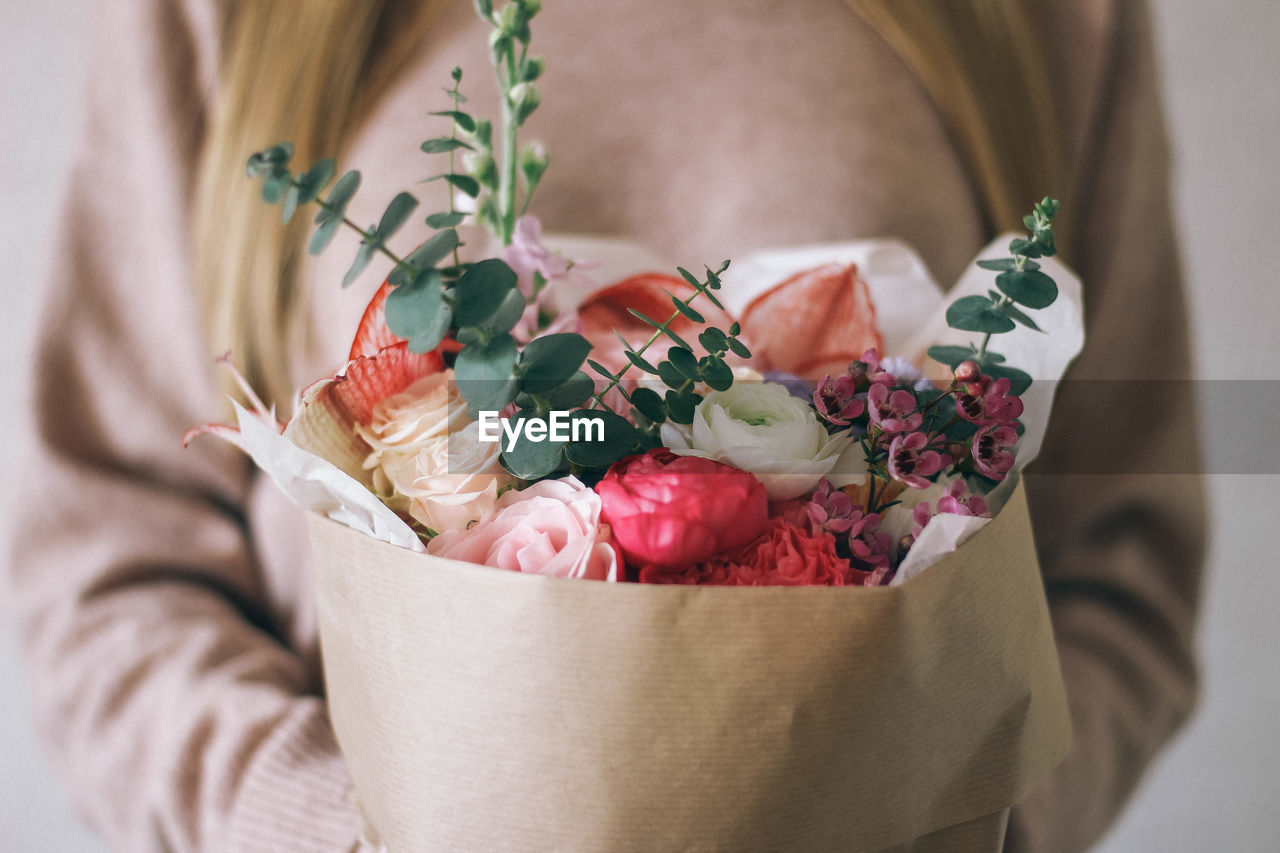 Midsection of woman with bouquet of flowers