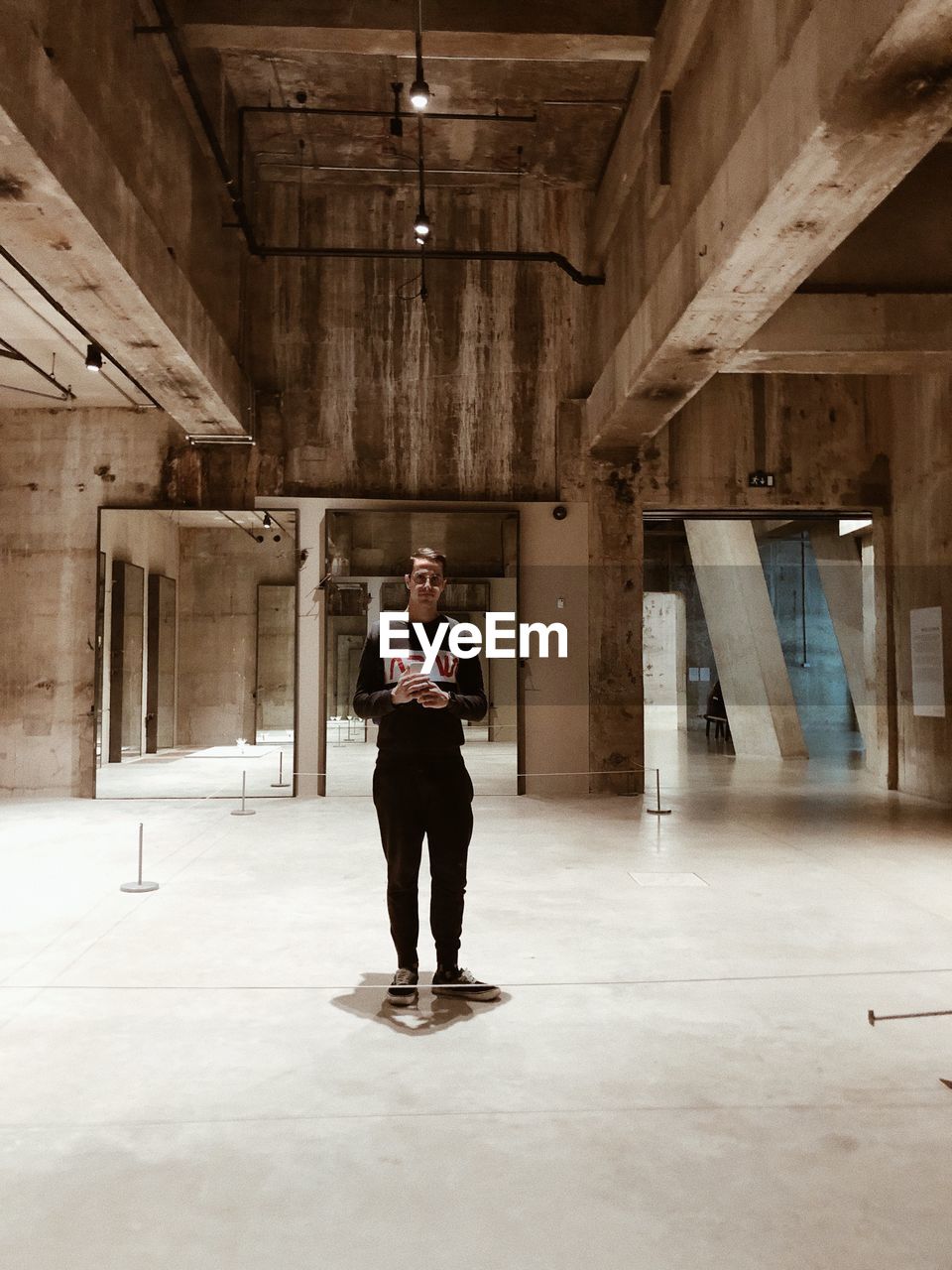 FULL LENGTH OF MAN STANDING IN CORRIDOR OF BUILDING