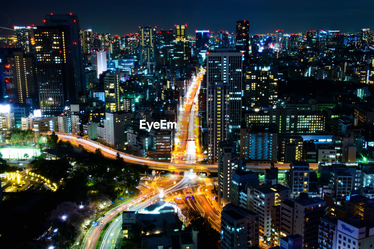 Aerial view of illuminated street amidst buildings at night