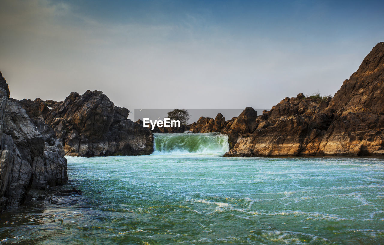 Scenic view of rocks in sea against sky
