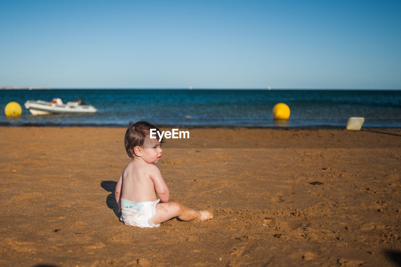 Full length of boy on beach against clear sky