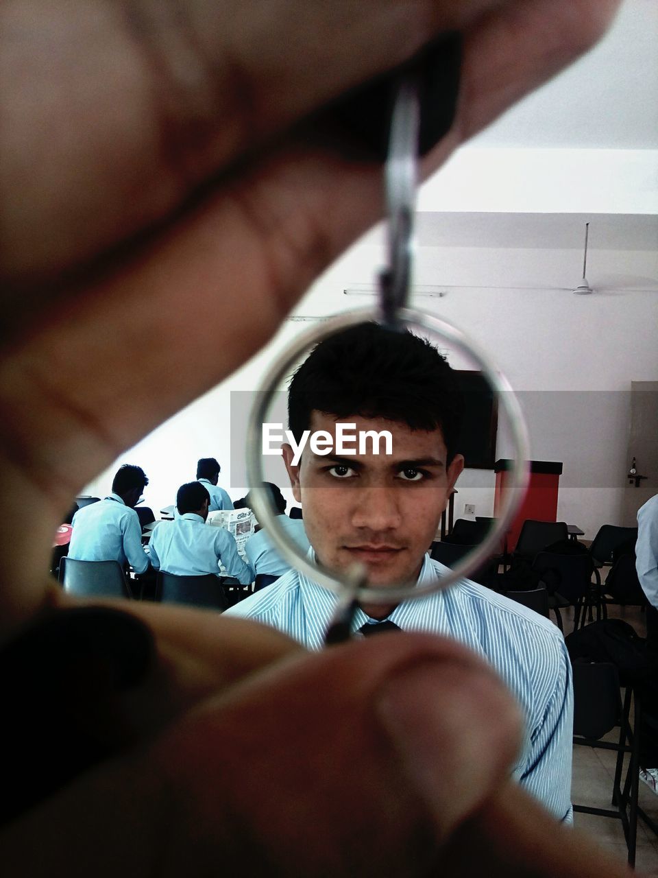 Cropped hand holding key ring against student