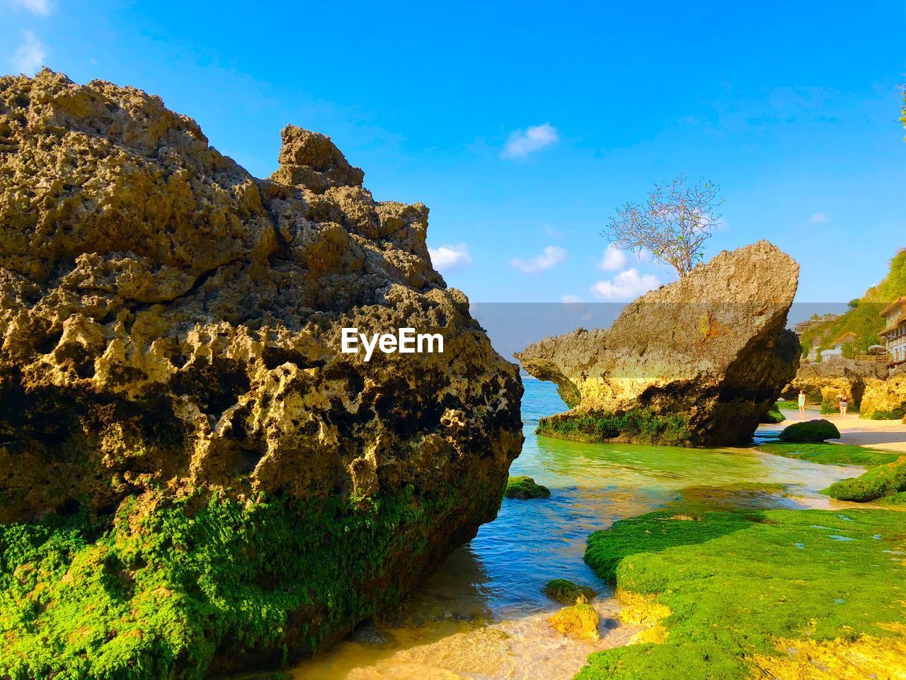 Rock formations by sea against blue sky