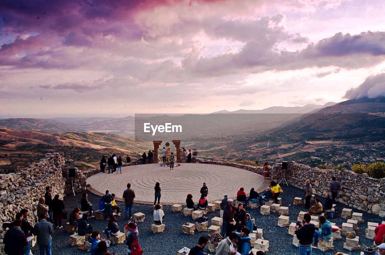 People on mountain against cloudy sky