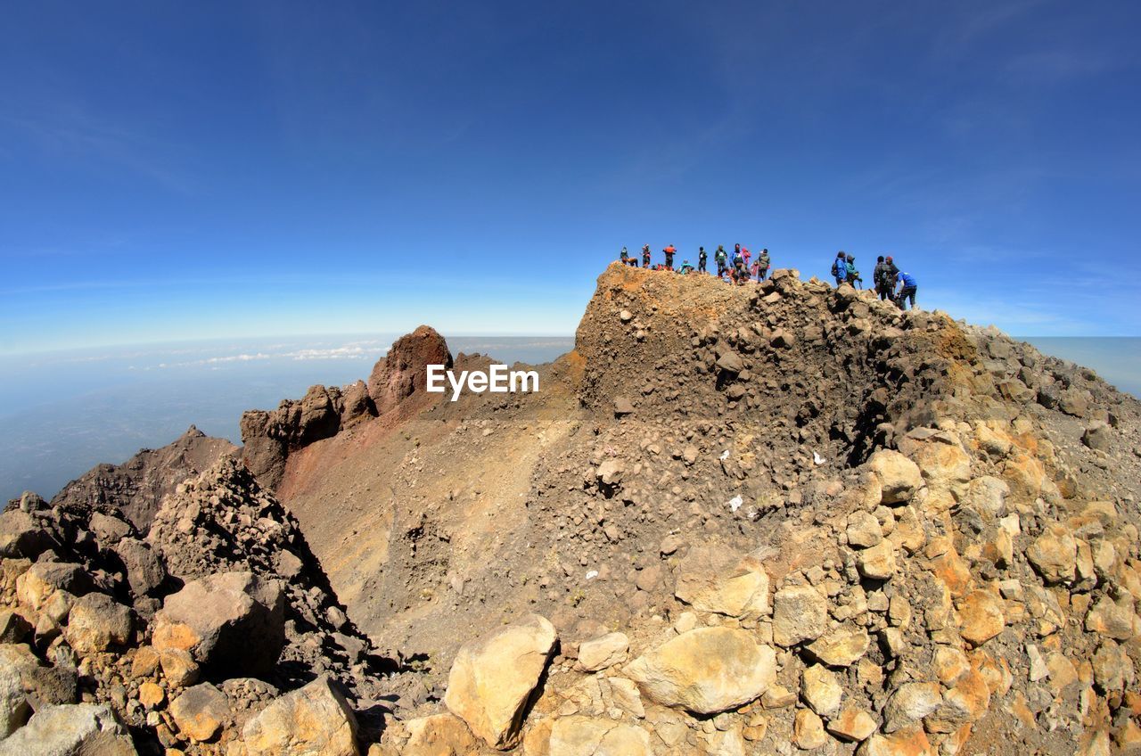 People on rock formation against sky