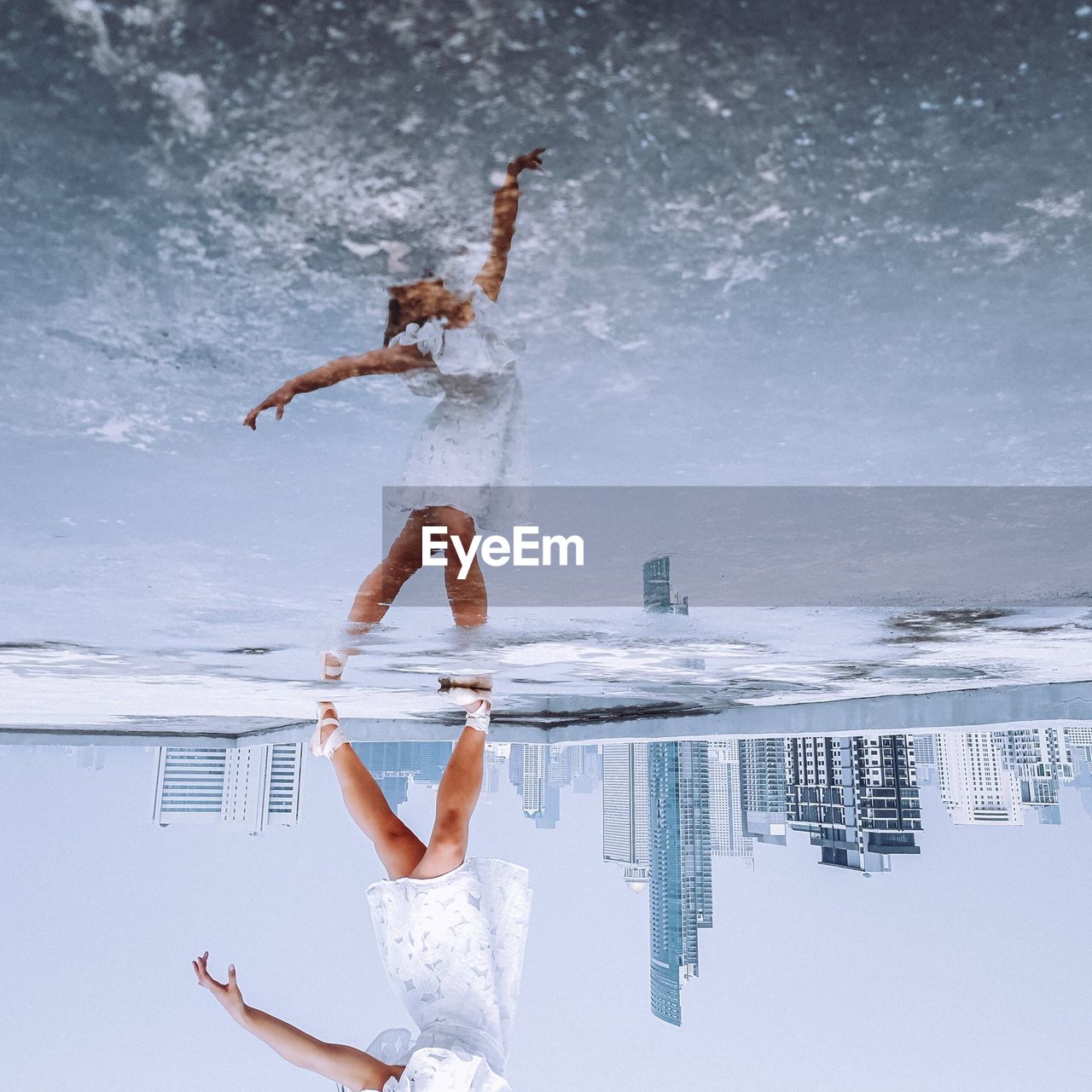 Low section of woman dancing while reflecting on puddle in city