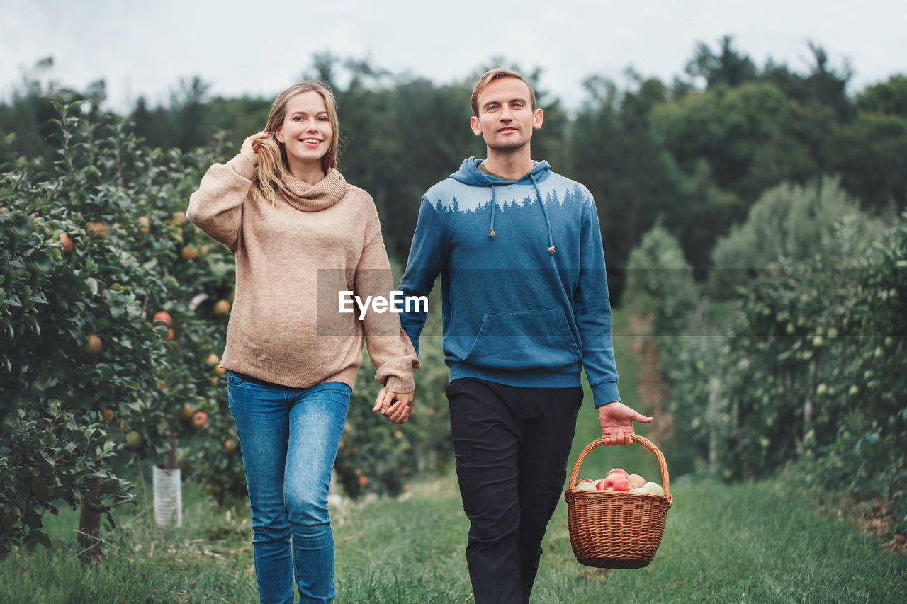 Portrait of smiling pregnant woman with husband walking on land