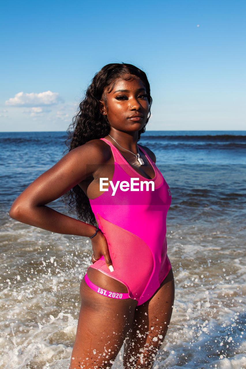 YOUNG WOMAN STANDING ON BEACH