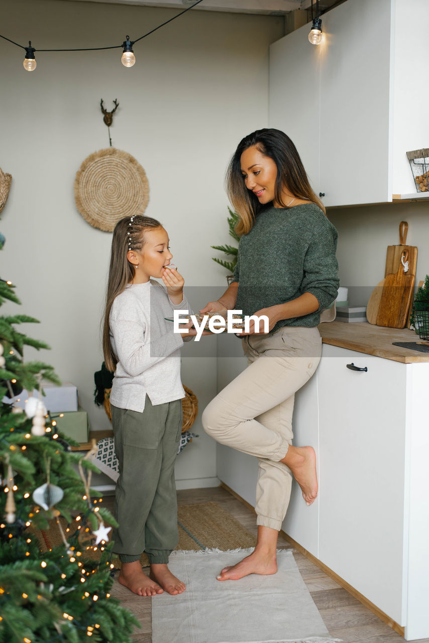 Happy family mother and child daughter taste christmas cookies in the kitchen in the house