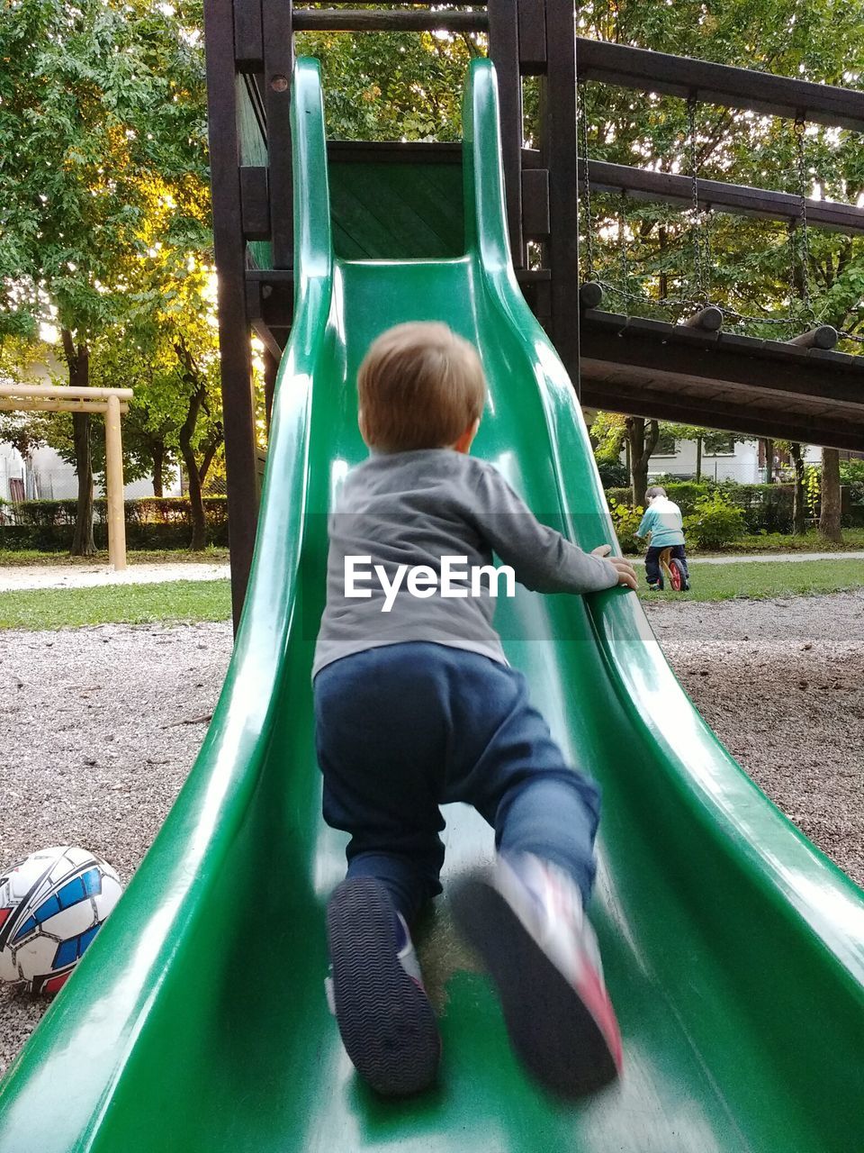 Rear view of boys playing on slide at playground