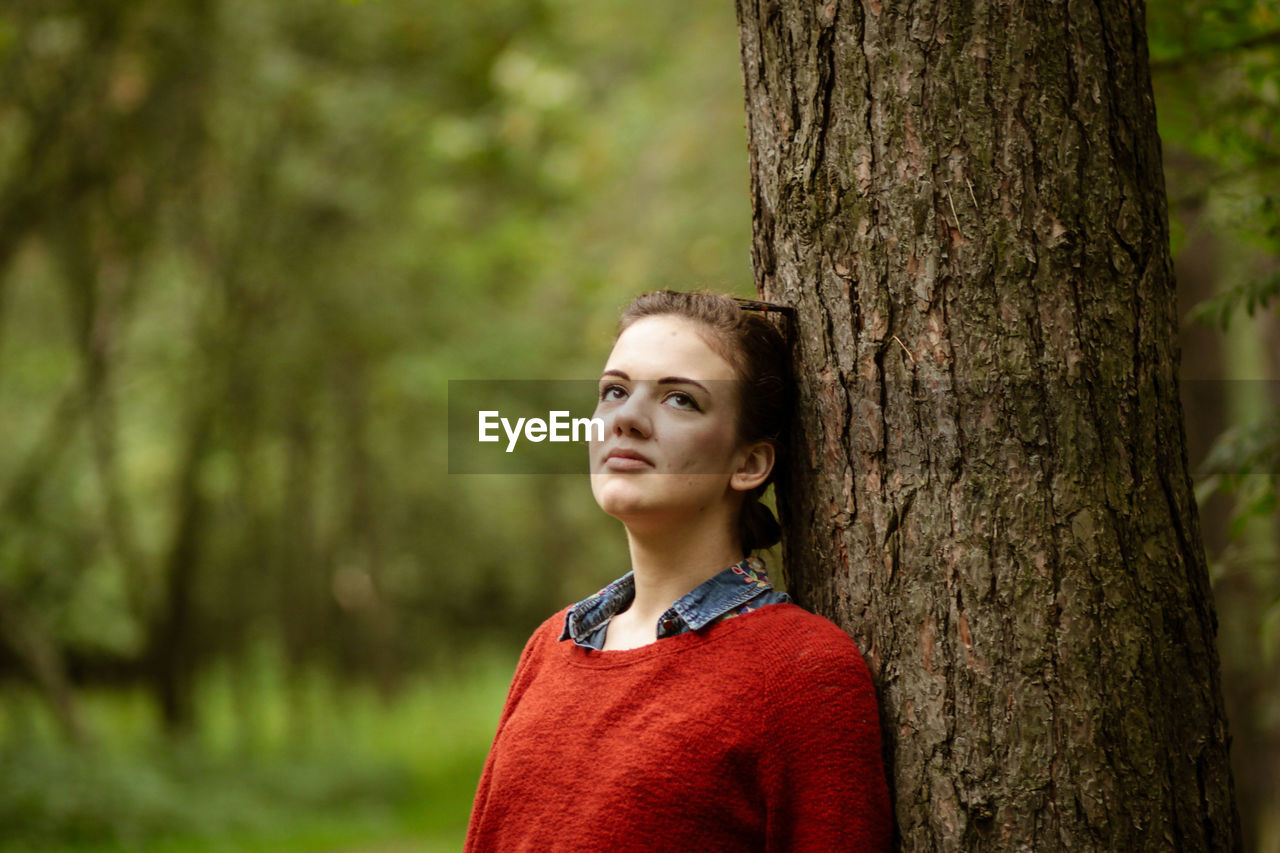 Portrait of evelina  against tree trunk in forest