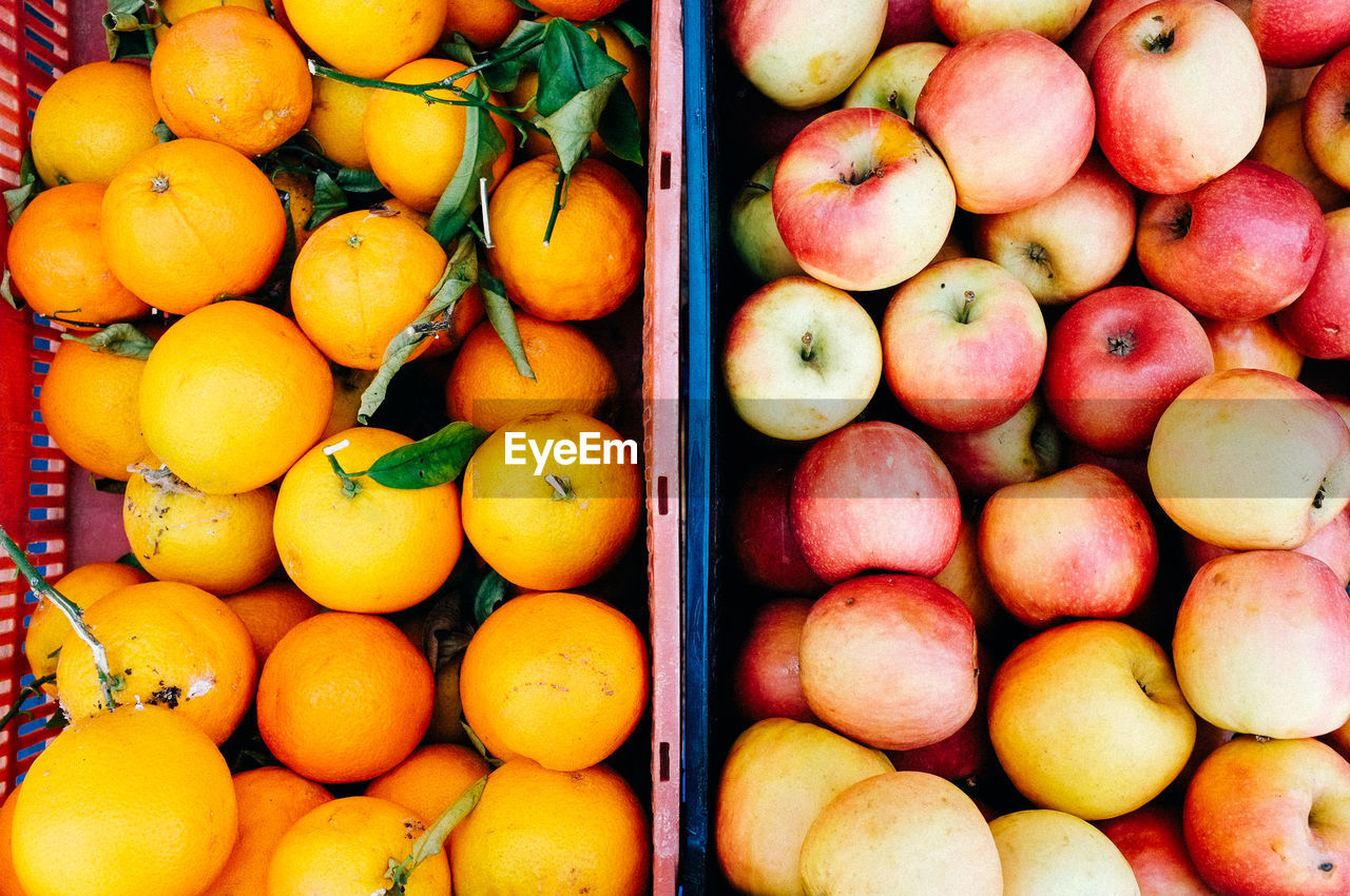 High angle view of apples and oranges in container at market for sale