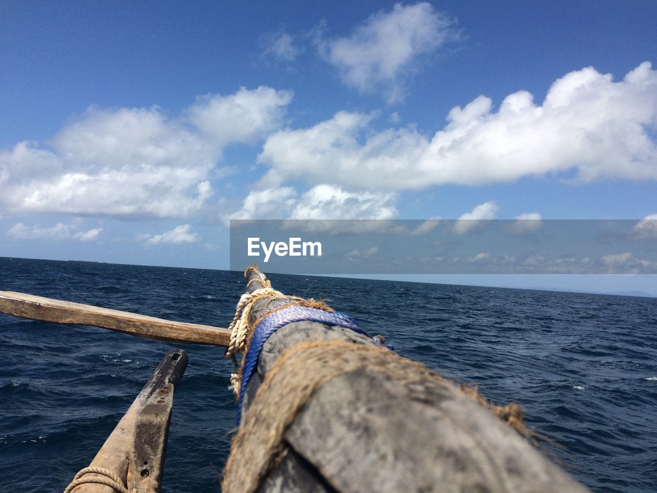 Cropped image of outrigger canoe sailing in sea against sky