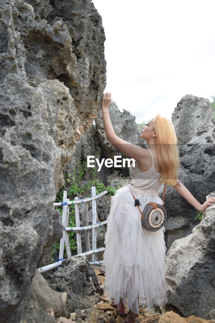 Woman standing on rock against sky