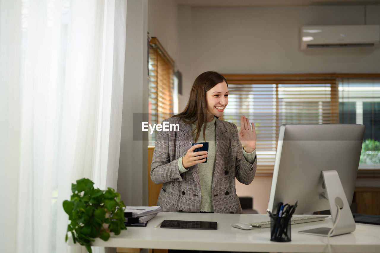 portrait of young woman using laptop while standing at home