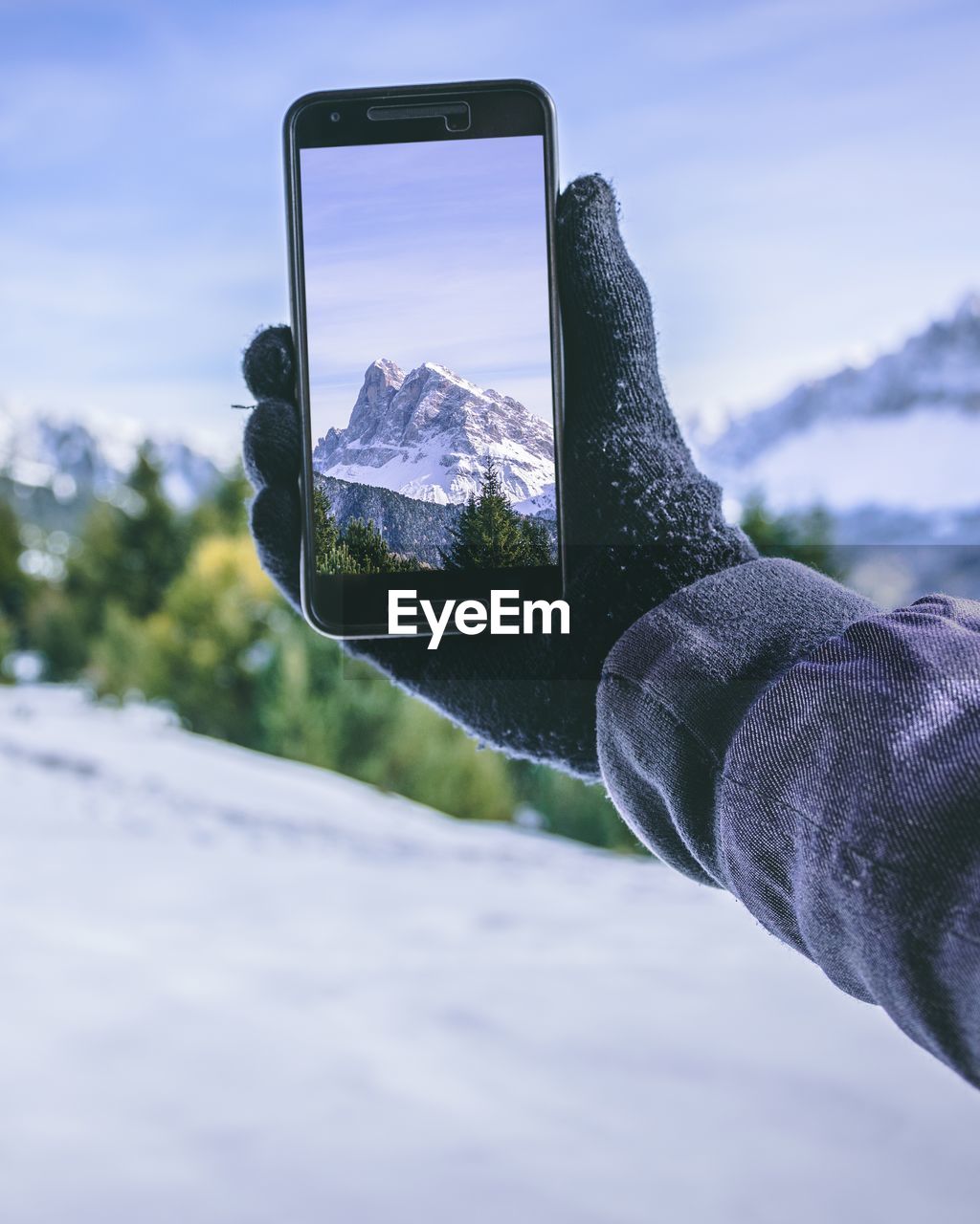 Close-up of person hand photographing snow covered mountain
