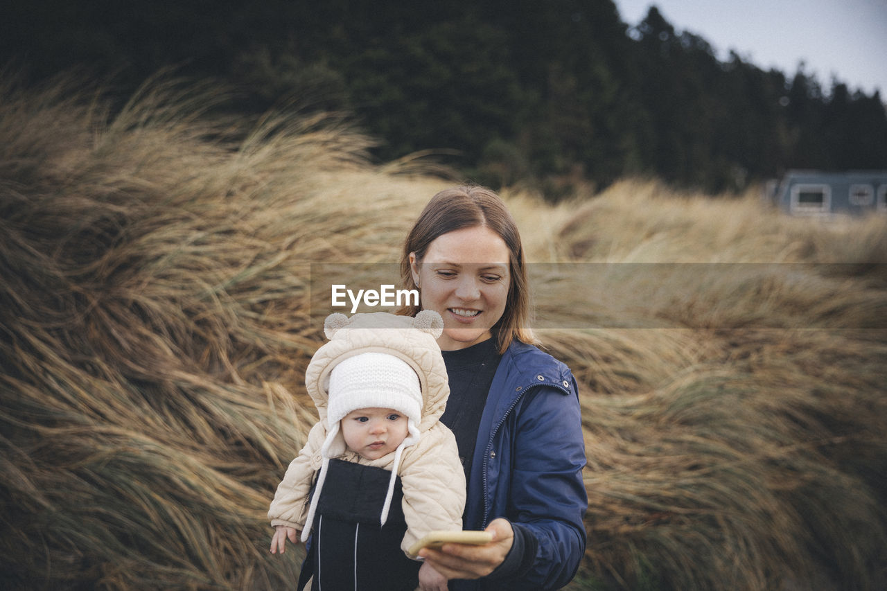 A woman with an infant is looking at a smartphone