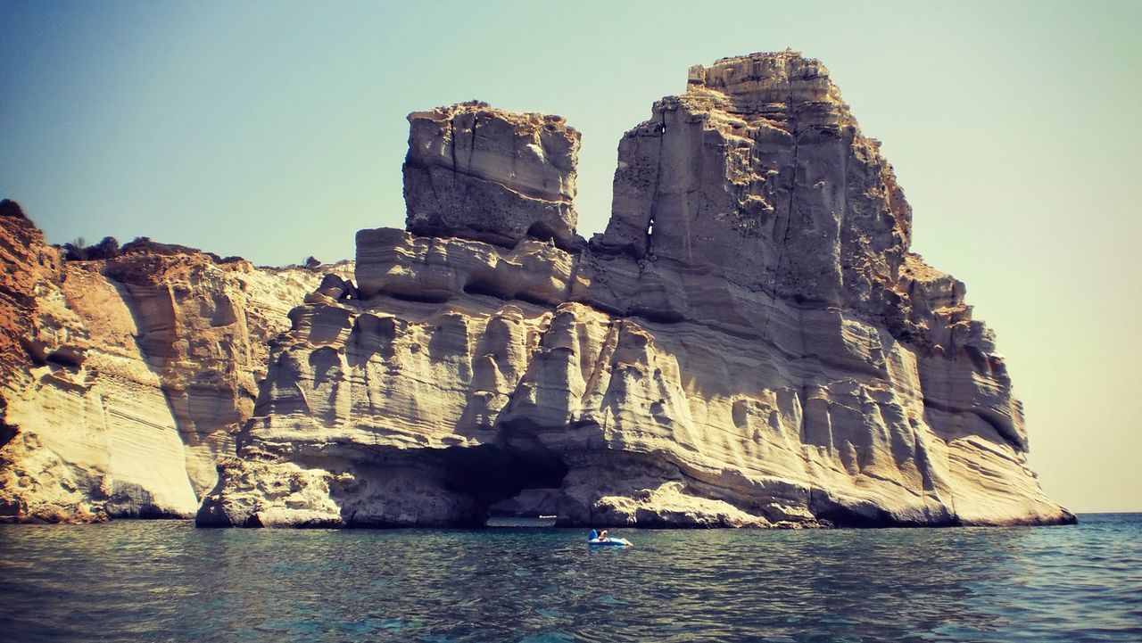 View of calm sea against rocky mountain